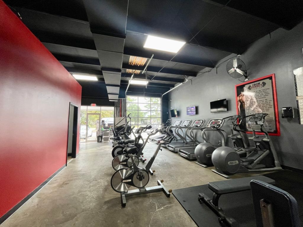 A gym with a lot of exercise equipment and a red wall.