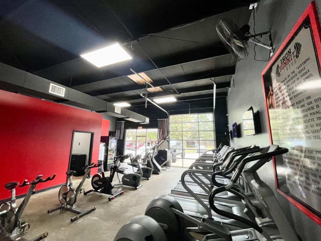 A gym with a lot of exercise equipment and a red wall.