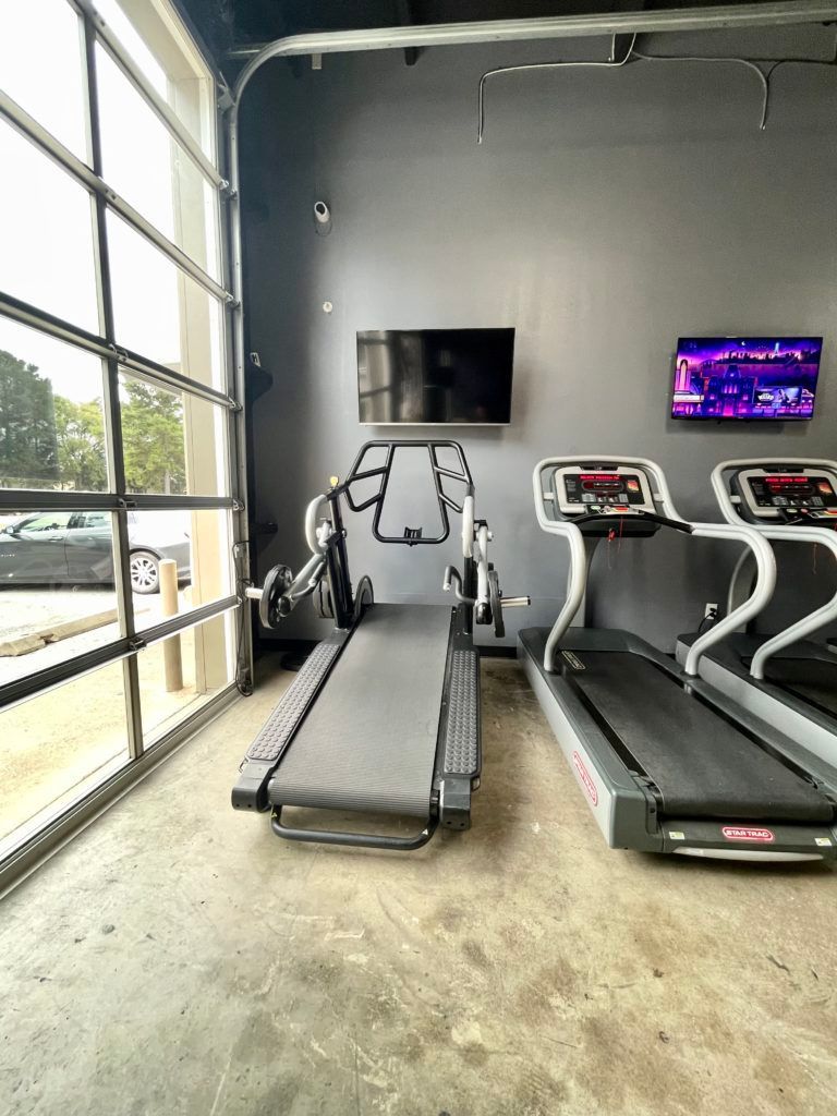 A gym with treadmills and a television on the wall.