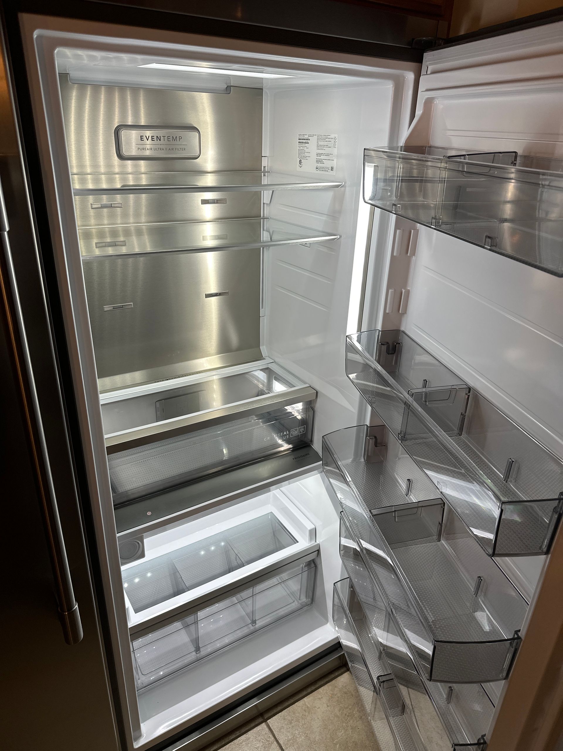 The inside of a stainless steel refrigerator with the door open.