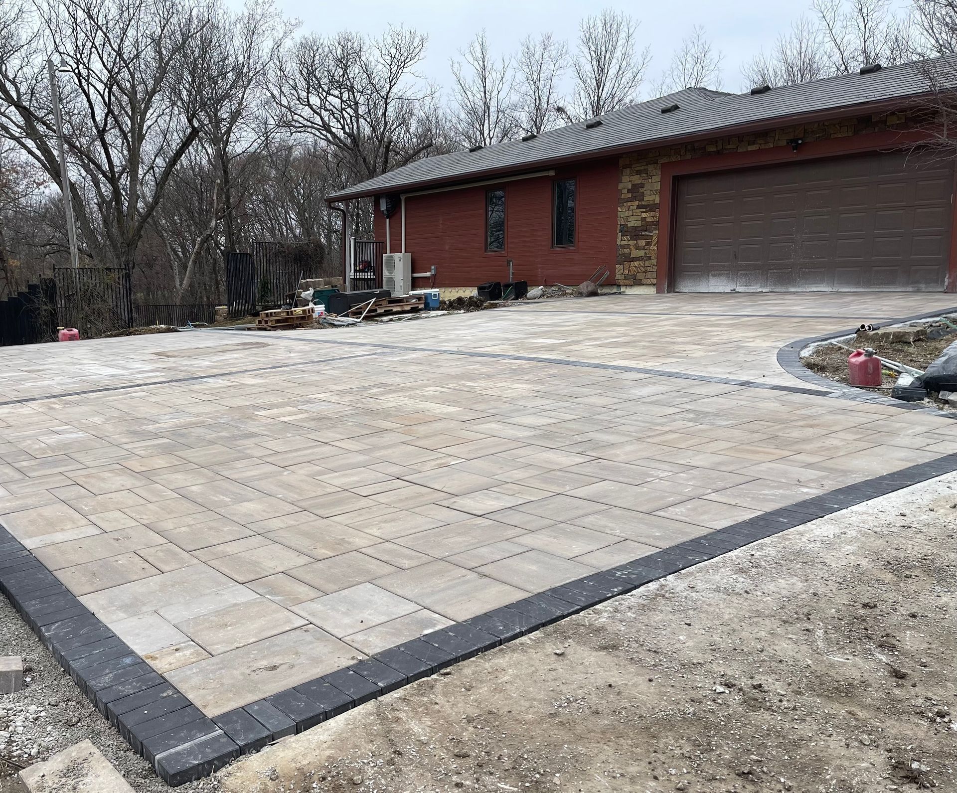 Large stone-paved driveway in front of a red brick house with a garage.