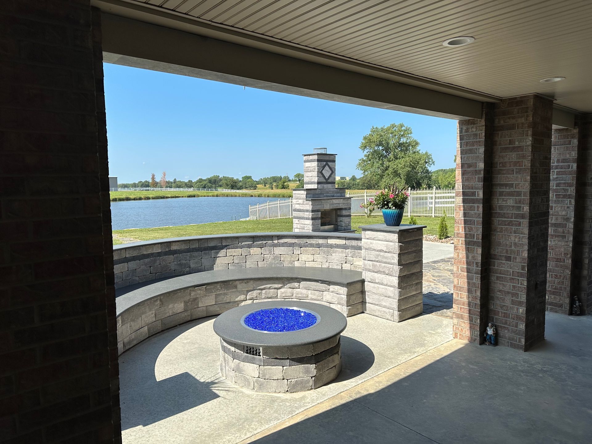 Covered patio with brick fire pit and blue-tiled water feature overlooking a lake