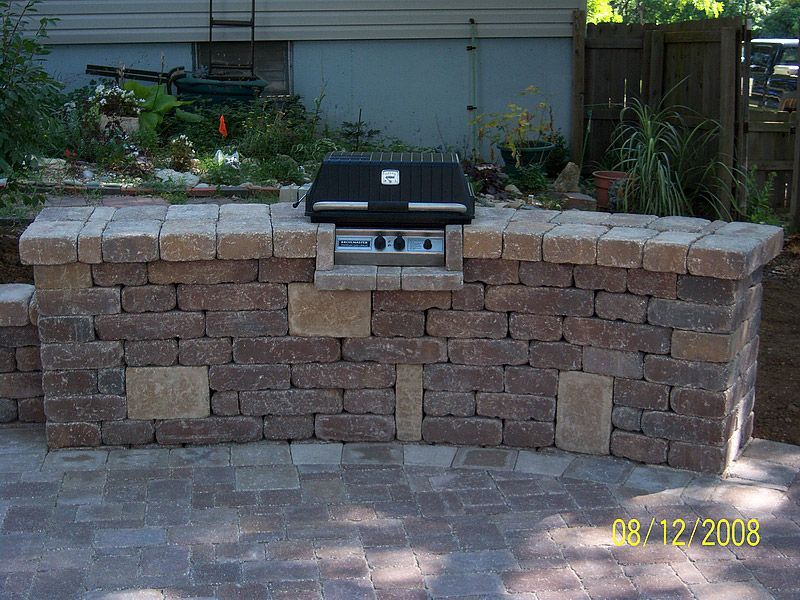 Outdoor brick grill island on a stone patio.