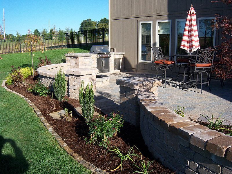 Outdoor patio with built-in grill, seating area, and landscaped garden beds.