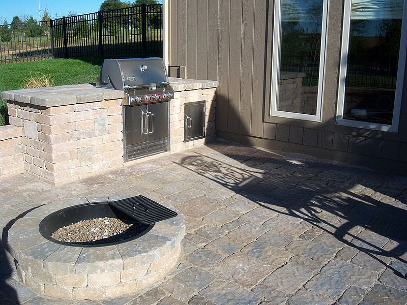 Outdoor patio with built-in grill, fire pit, and brick pavers.