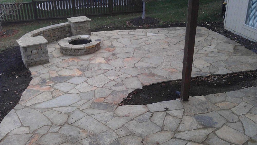 Stone patio with fire pit and retaining wall.