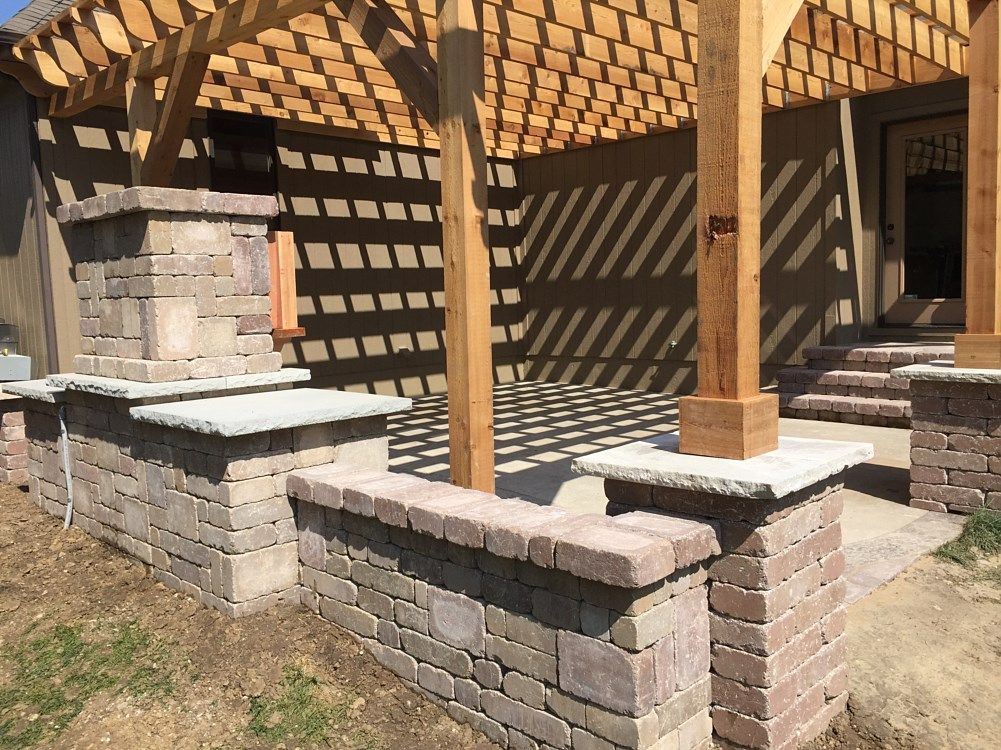 Patio with a wooden pergola, brick pillars, and stone walls.
