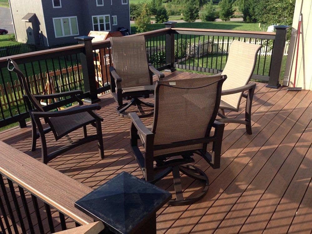 Deck with four chairs and dark railing overlooking a yard.