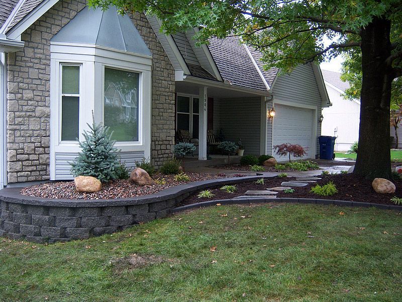 House exterior with gray stone and siding, a landscaped yard, and a large tree.