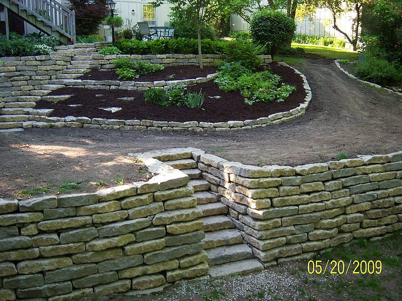 Stone retaining walls and steps in a landscaped yard.