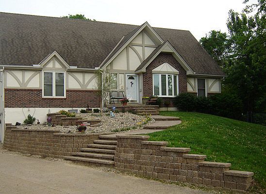 House with brick facade, Tudor-style detailing, and retaining wall leading to front steps.