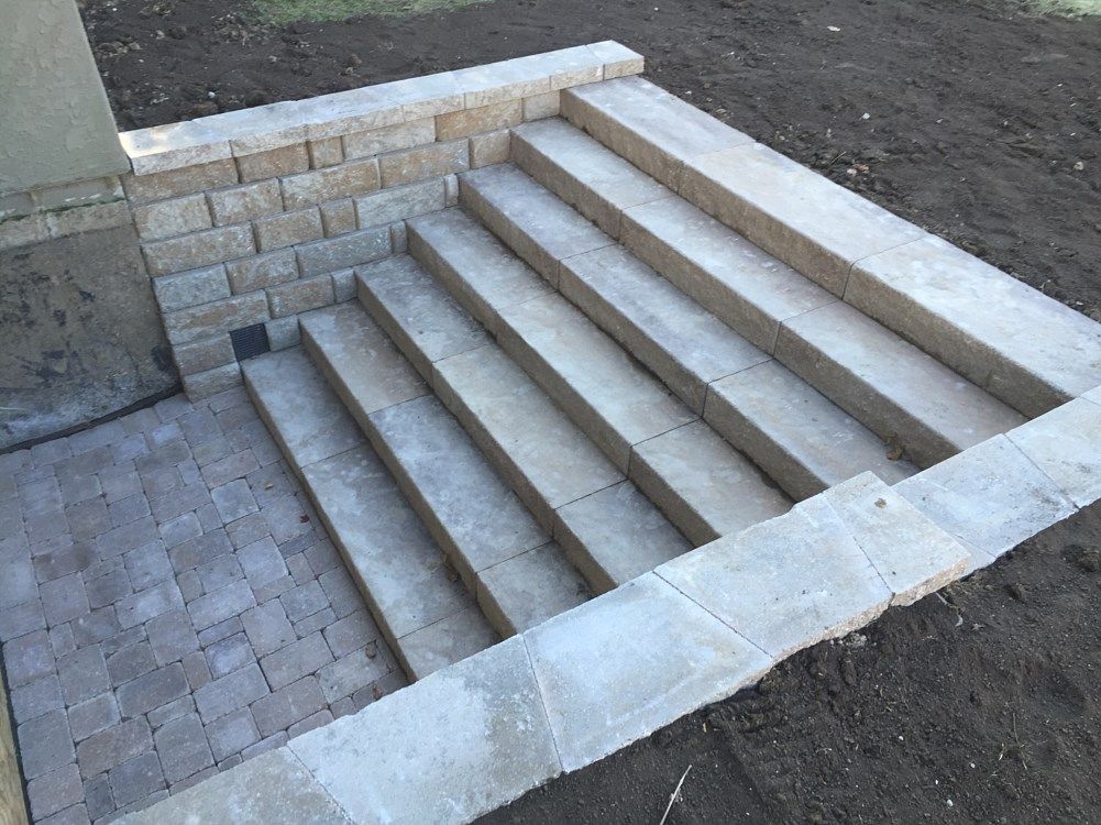 Stone steps leading down to a brick patio, built into a retaining wall.