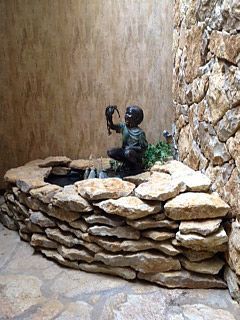 Stone fountain with sculpture of a child holding a bird; built-in to a stone wall.
