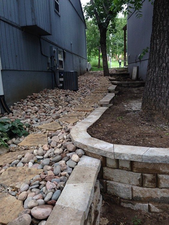 Stone retaining walls and a pathway of rocks between two buildings.