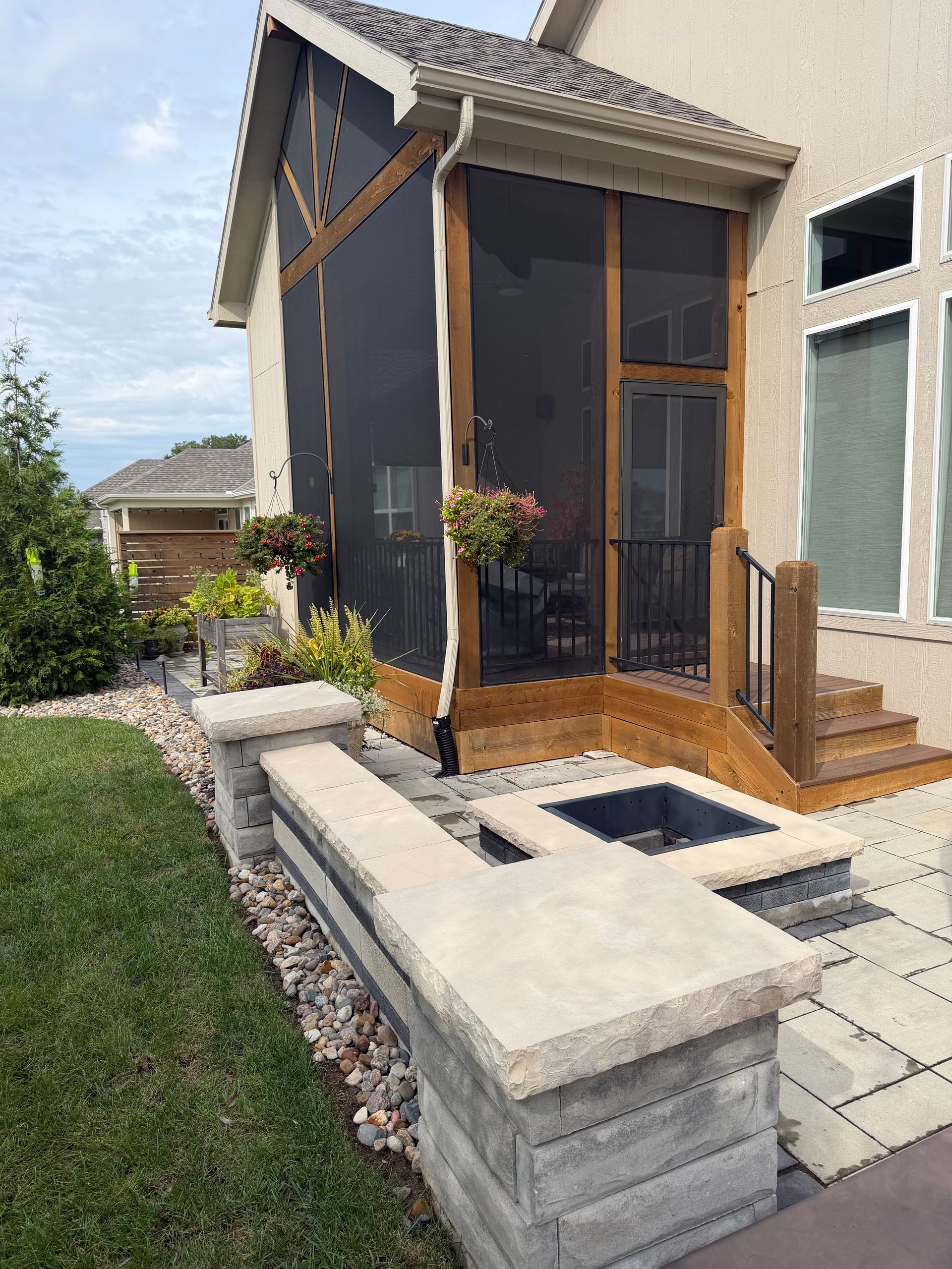 Small modern backyard shed with dark siding, wood porch, and stone steps beside a lawn
