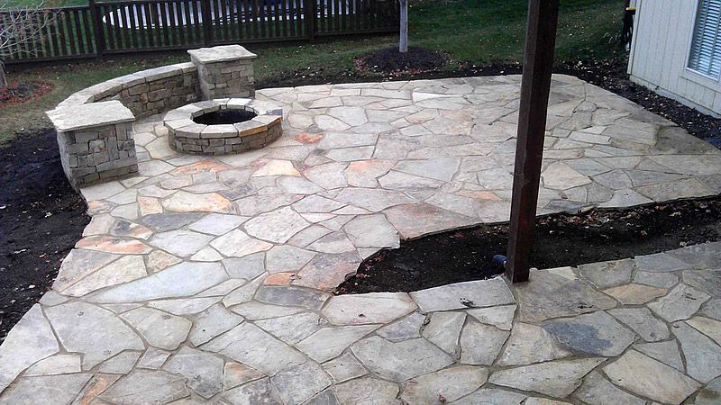 Stone patio with a fire pit and a seating wall.