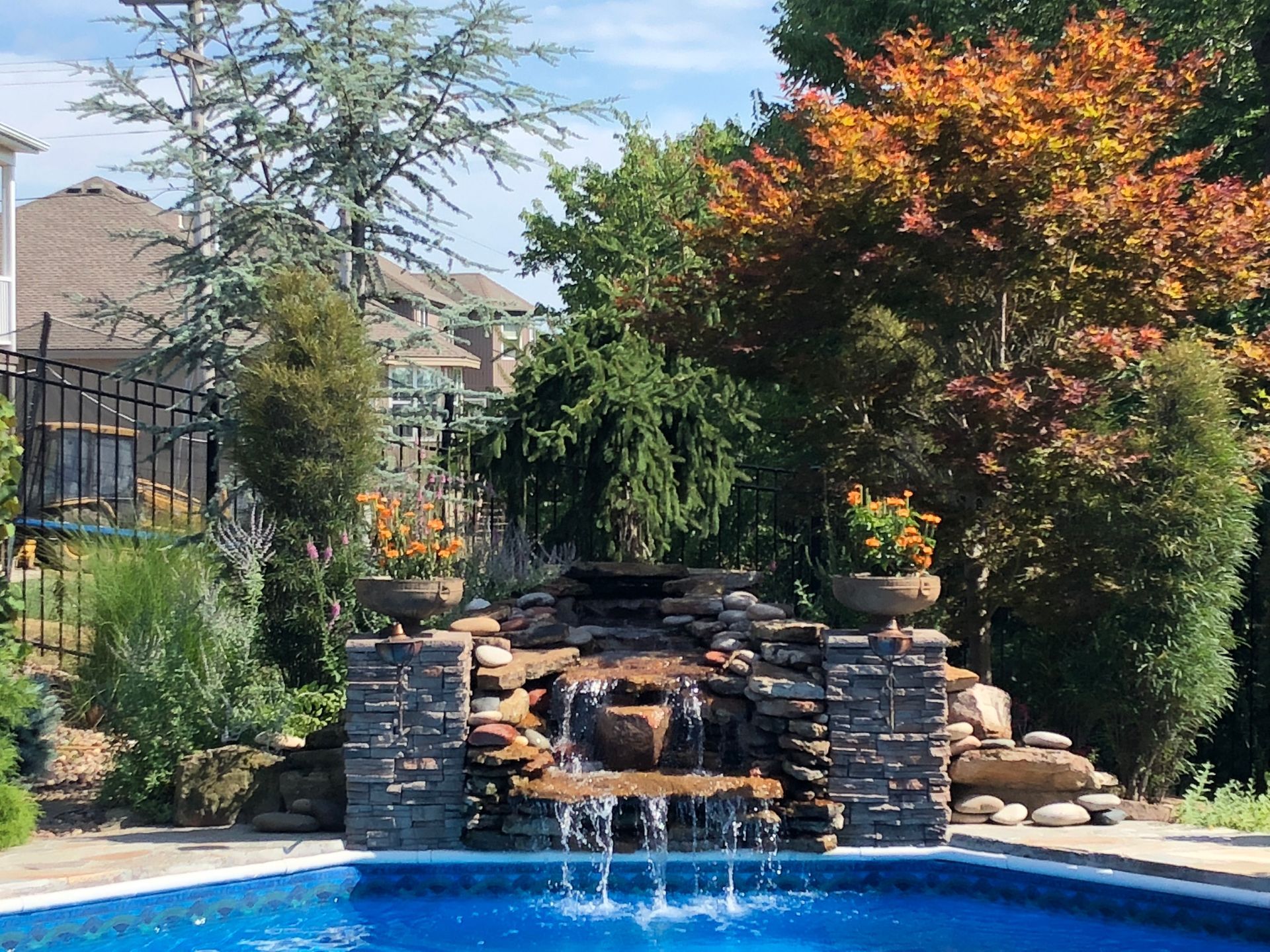 Stone waterfall fountain in a landscaped garden with autumn trees and shrubs