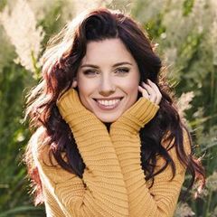 the woman is wearing a yellow sweater and smiling