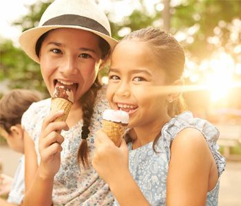 two young girls are eating ice cream cones together