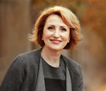 a woman wearing a gray sweater and a black dress is smiling for the camera