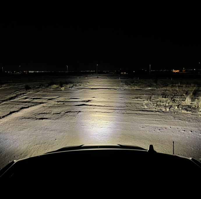 a car is driving down a snowy road at night .