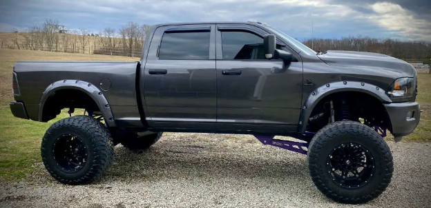 a gray dodge ram truck is parked on a gravel road with a lifted body .