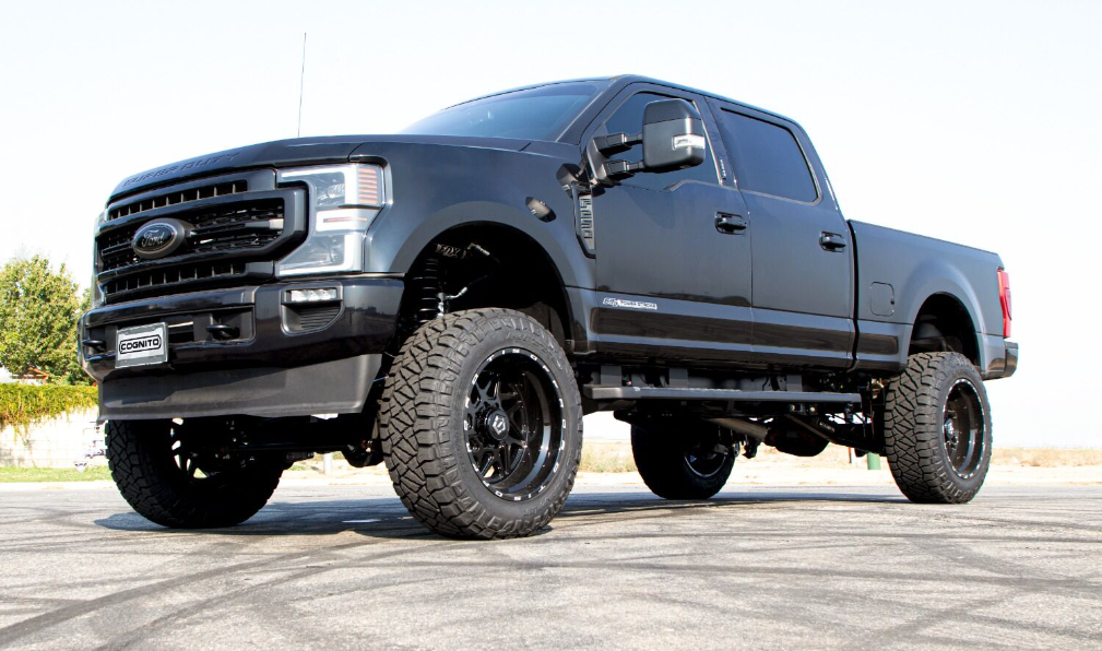 a lifted black truck is parked on the side of the road .