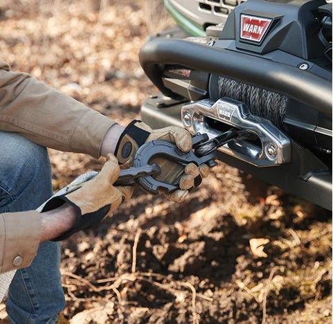 a person is using a winch to pull a vehicle out of the mud .