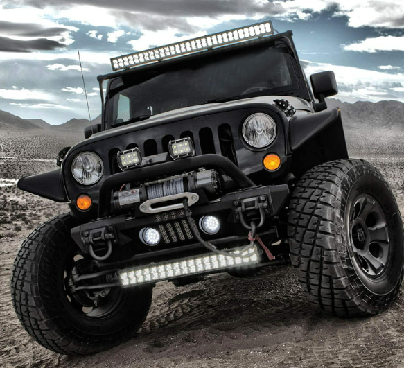 a black jeep with a light on top of it is parked in the desert .