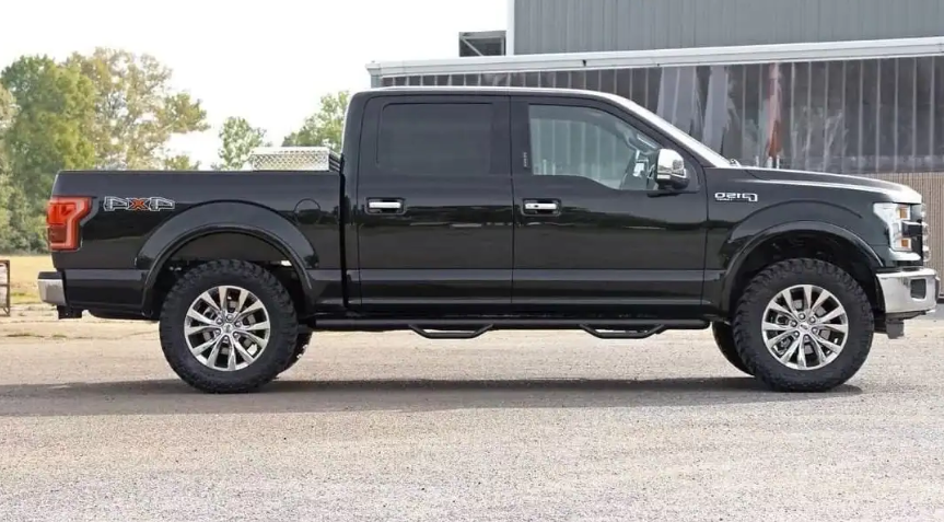 a black ford f150 pickup truck is parked in front of a building .