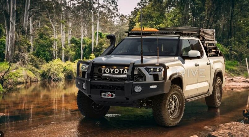 a toyota truck is driving through a muddy river .
