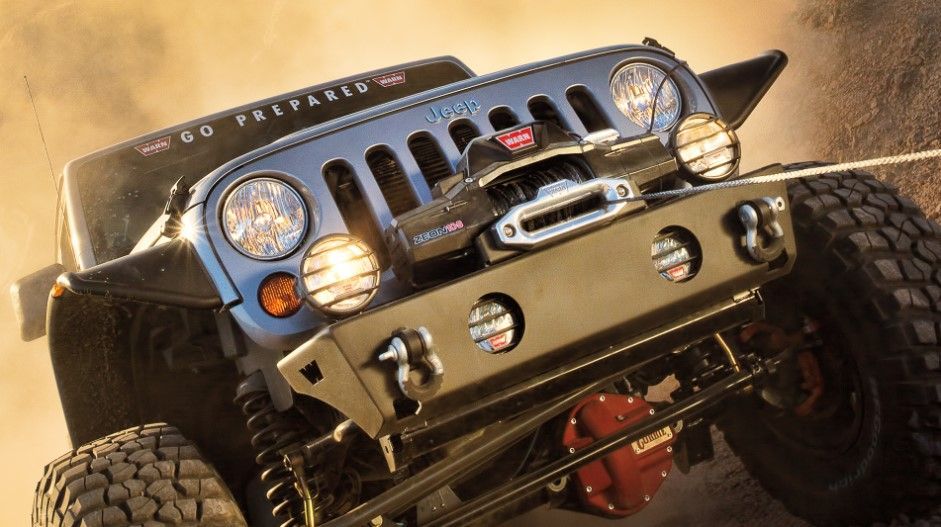 a blue jeep is driving down a dirt road .