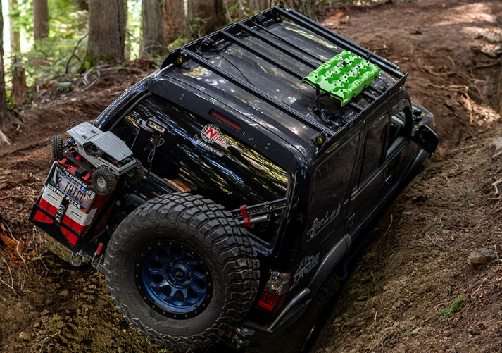 a black jeep is stuck in the mud on a dirt road .