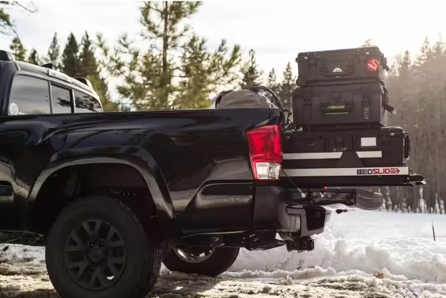 a black truck is parked in the snow with its bed open