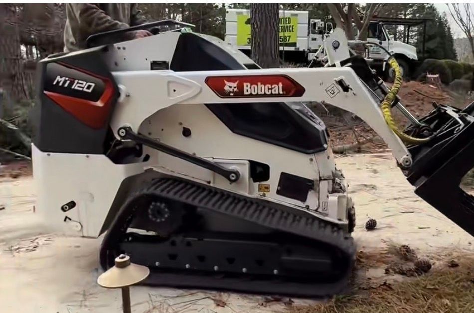White and black Bobcat MT120 compact track loader on a concrete surface.
