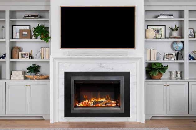 Modern living room with built-in shelves, a wall-mounted TV, and a lit electric fireplace.