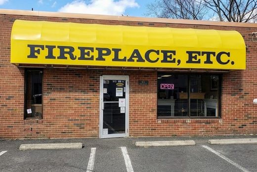 Storefront with yellow awning reading FIREPLACE, ETC. on a brick building.