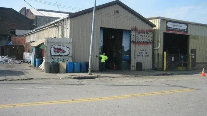 Street view of an industrial garage with open bays and a person in a neon vest inside