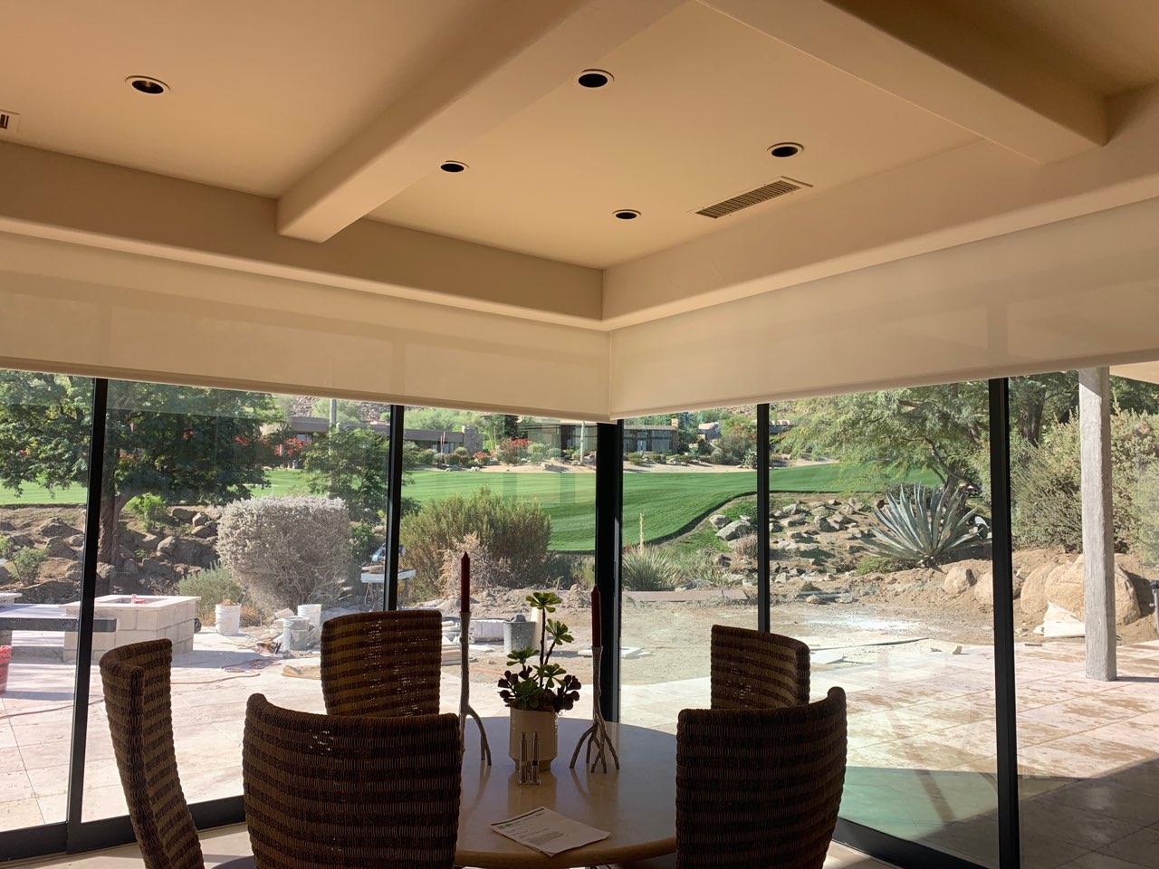 A dining room with a table and chairs and lots of windows