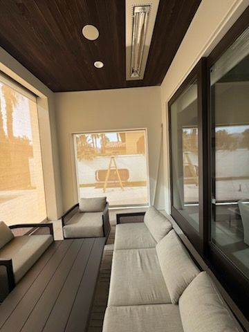 Outdoor lounge with gray furniture, a dark wood ceiling, and large windows.