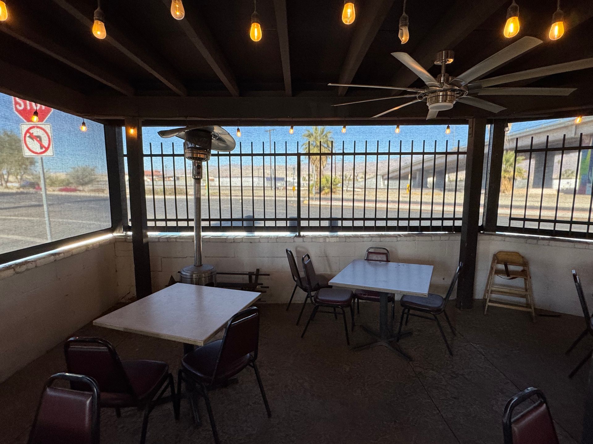 A restaurant with tables and chairs under a canopy with a ceiling fan.