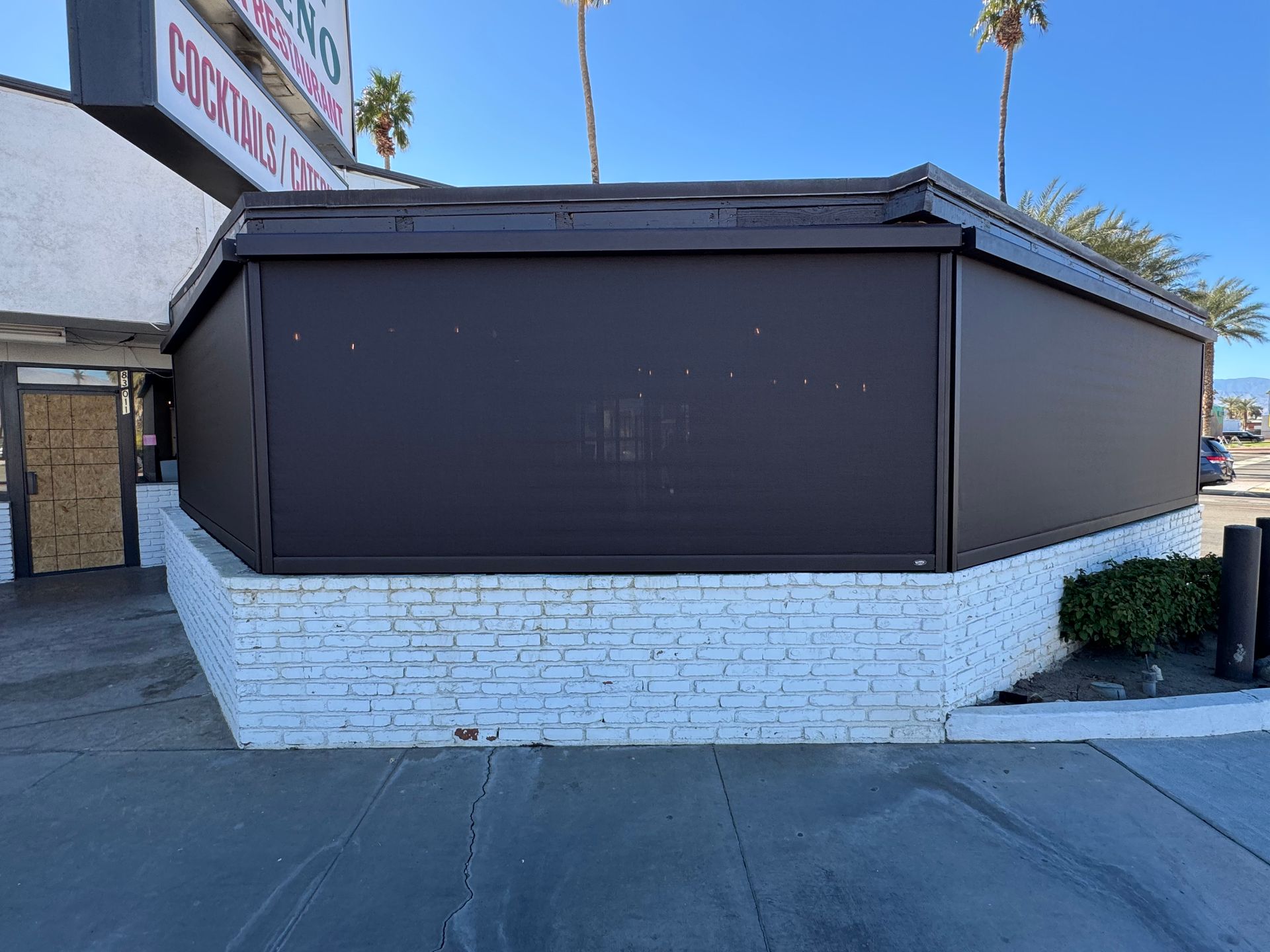A white brick building with a brown awning on the side of it.