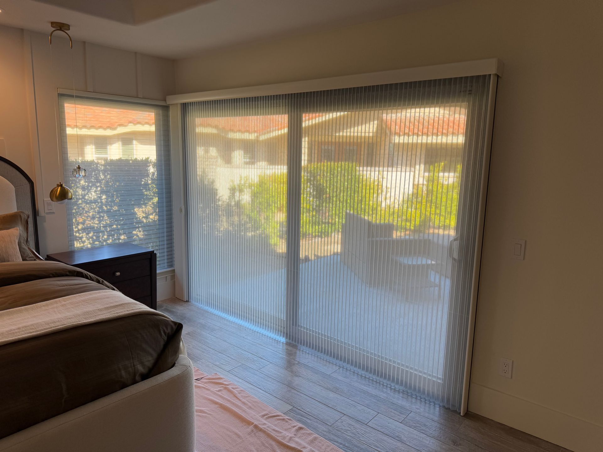 A bedroom with a bed and sliding glass doors with blinds.