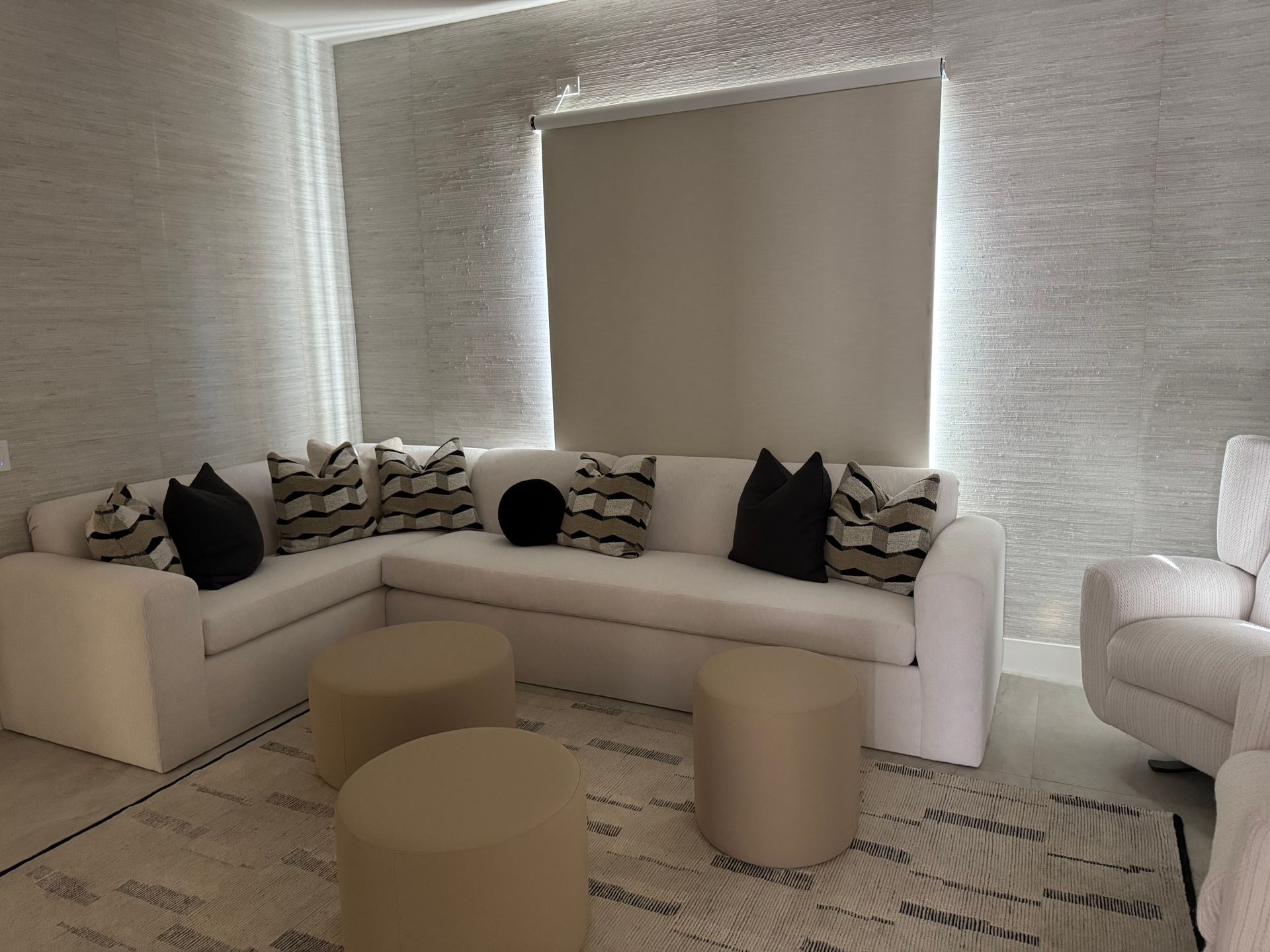 A living room with a white couch , chair , and ottomans.