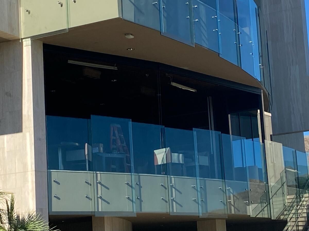 Modern building exterior with glass walls and a balcony.