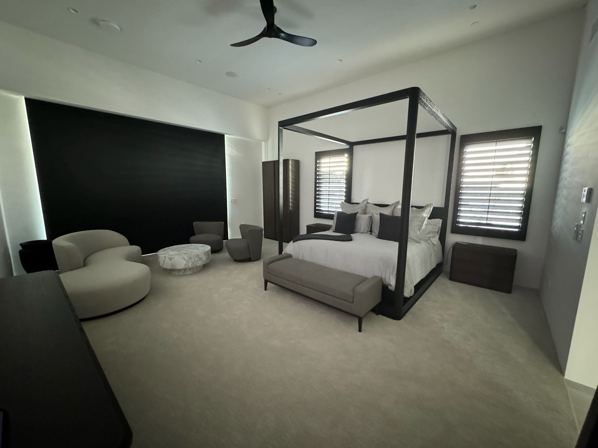 A bedroom with a canopy bed, chairs, and a ceiling fan.