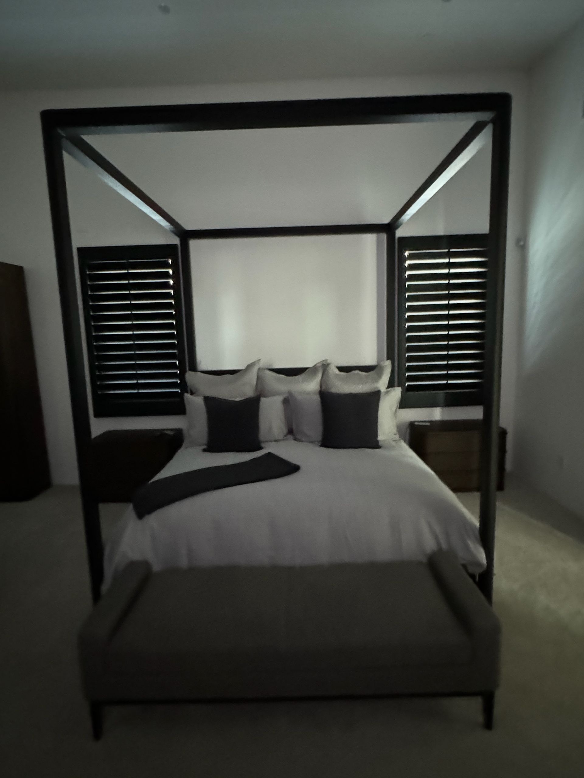 A bedroom with a canopy bed and a bench