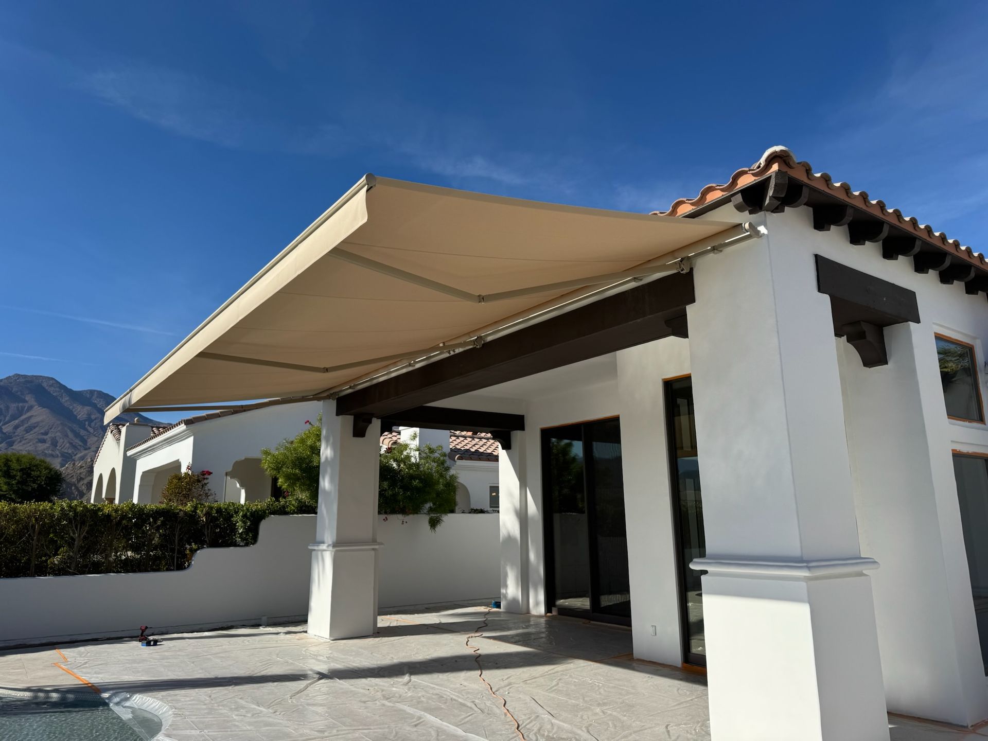 A house with an awning over a patio next to a pool.