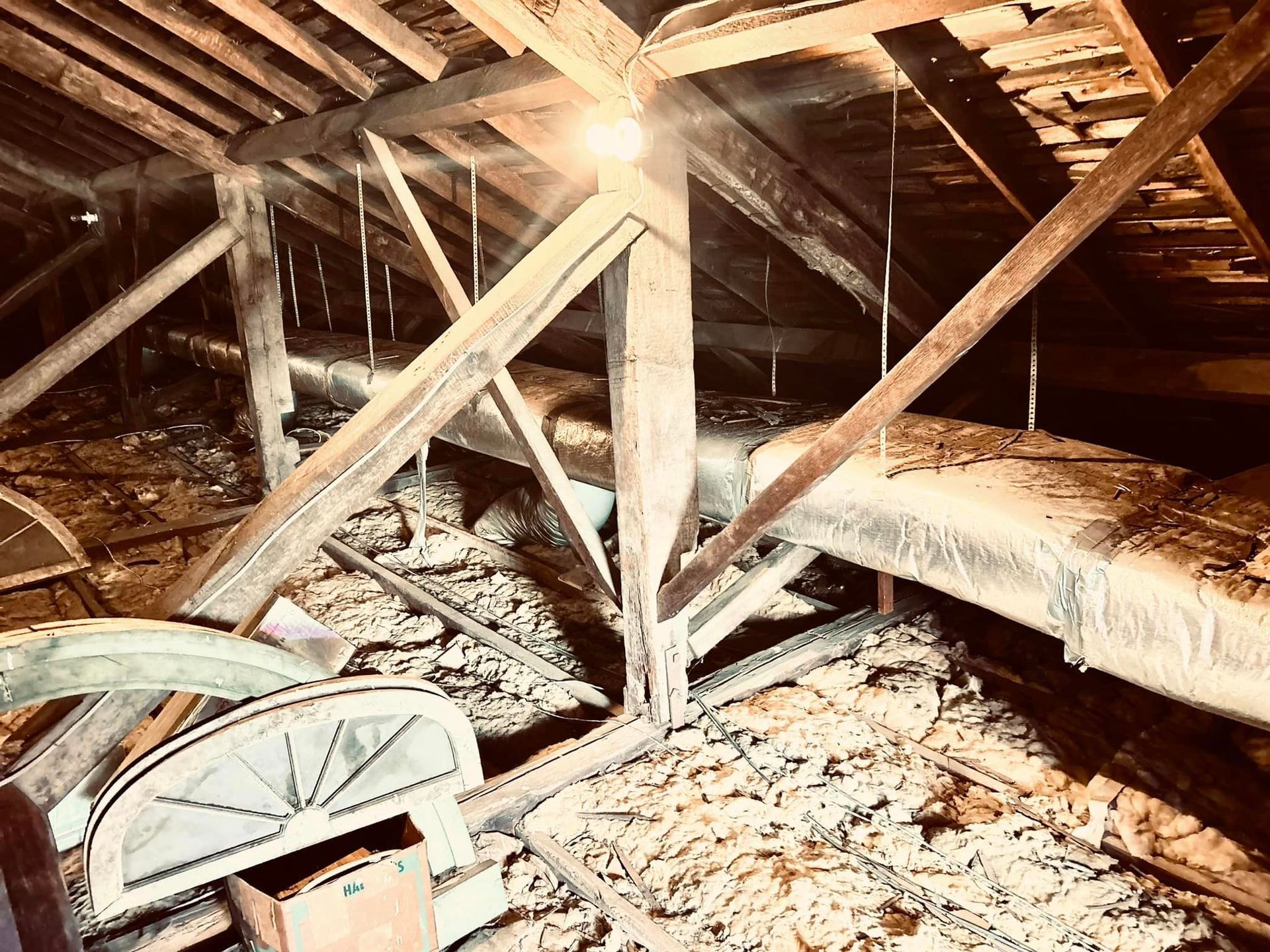 An attic with a lot of wooden beams and pipes.