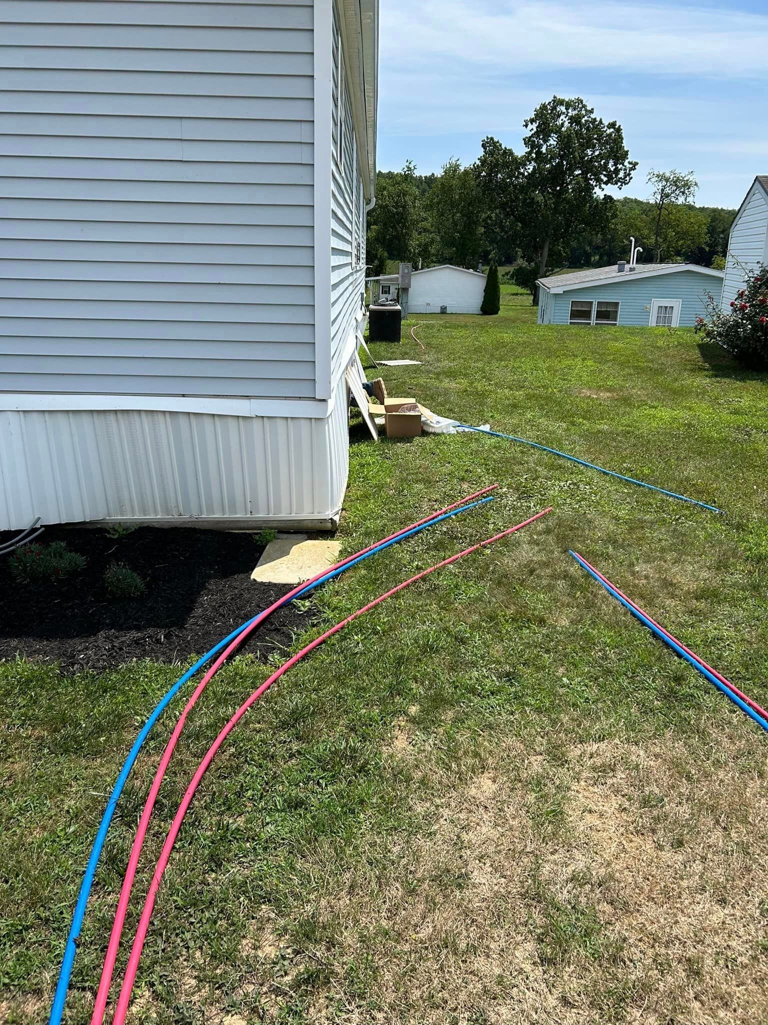 A mobile home is sitting in the grass next to a hose.